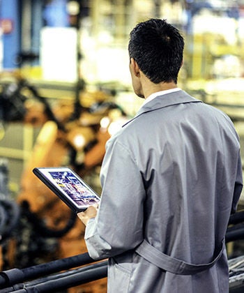 man bekijkt een werkplek en houdt een tablet vast