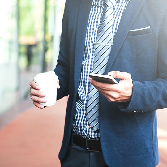 Zakenman houdt een beker koffie en een smartphone vast
