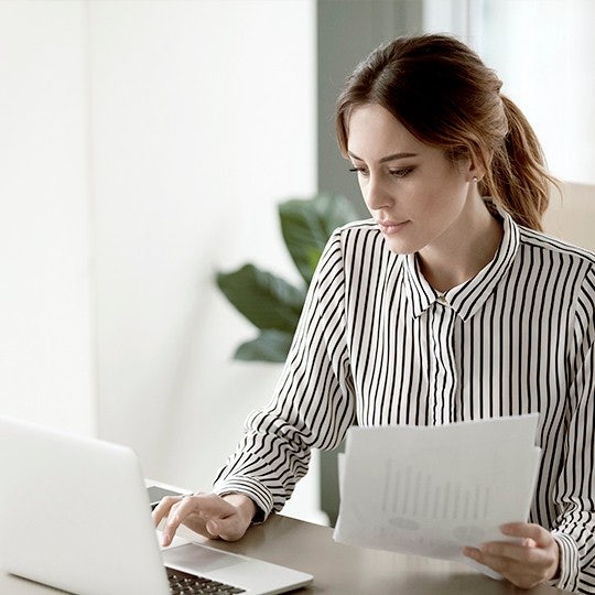 vrouw-achter-laptop-met-papier-in -hand