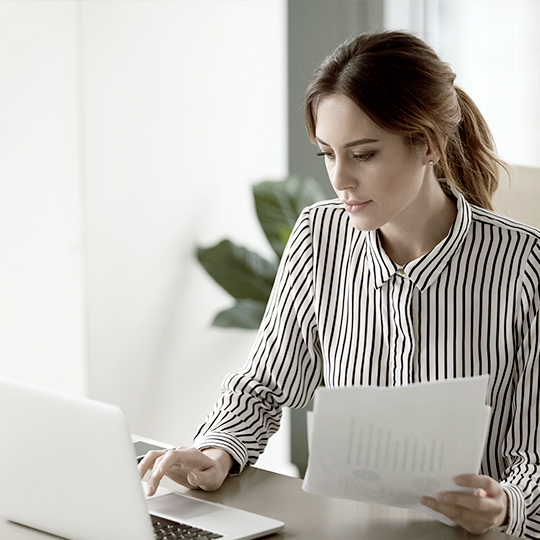 vrouw-achter-laptop-met-papier-in -hand