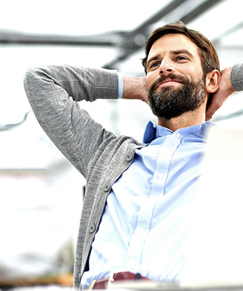 man die achterover leunt in zijn stoel