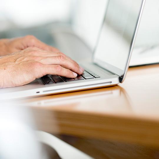 ISO 27001 - gegevensbescherming close up van handen die aan het werk zijn op een laptop
