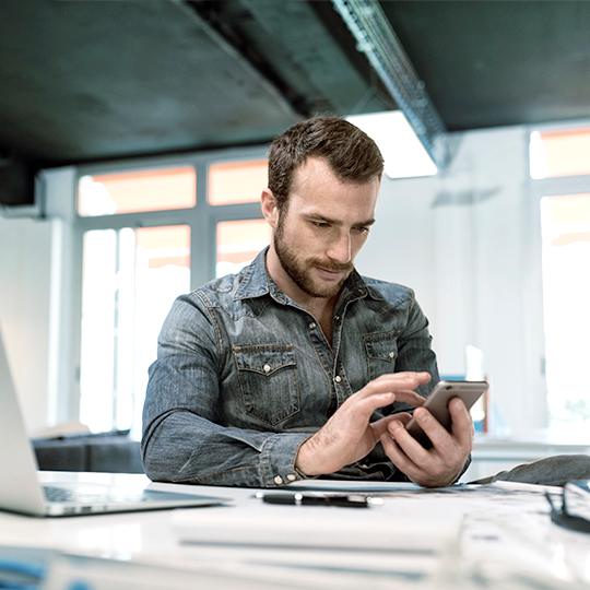 man-achter-buro-met-mobiel